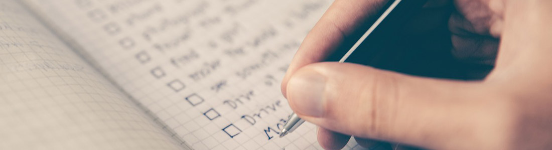 hand holding a pen over a checklist